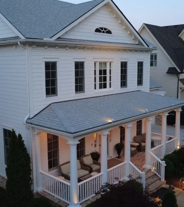 A finished white Hisway Painting exterior at dusk, porch lights on