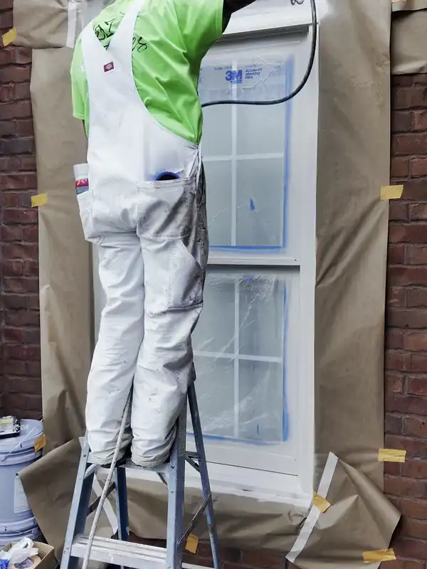 A Hisway painter spraying the trim around a masked window