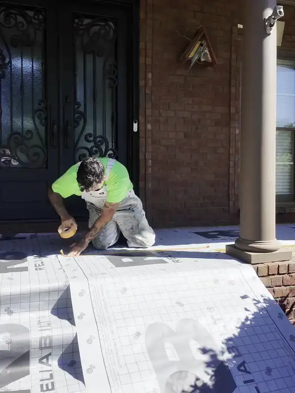 A Hisway painter masking the porch steps before the exterior is painted